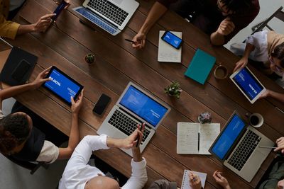 Co-workers sitting around a table with laptops and tablets