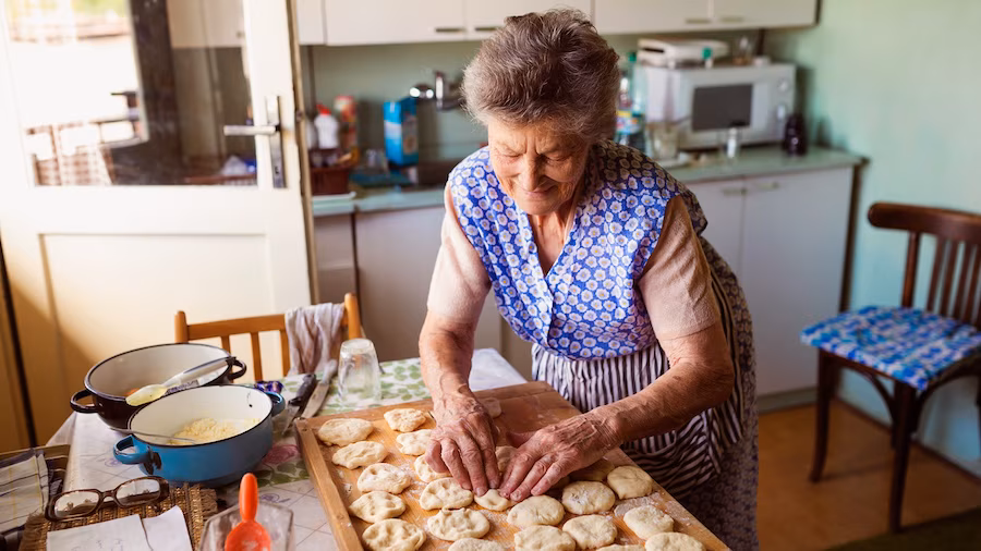 Elderly woman making cookies in kitchen